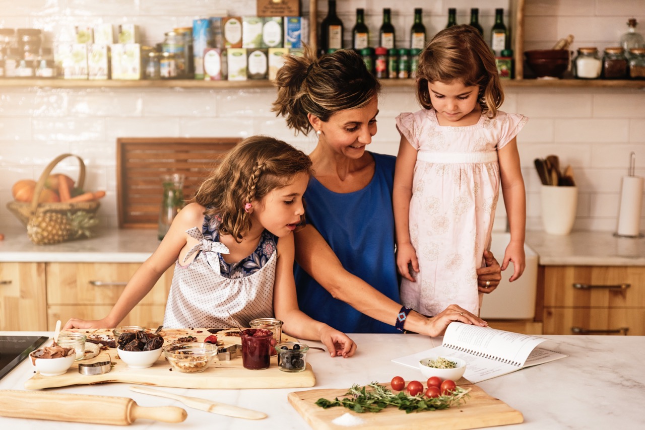 A helper preparing a meal with children in a vacation rental kitchen