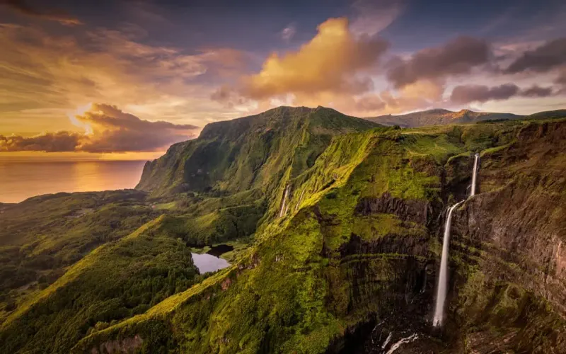 Green cliffs and a waterfall at sunset on Kauai