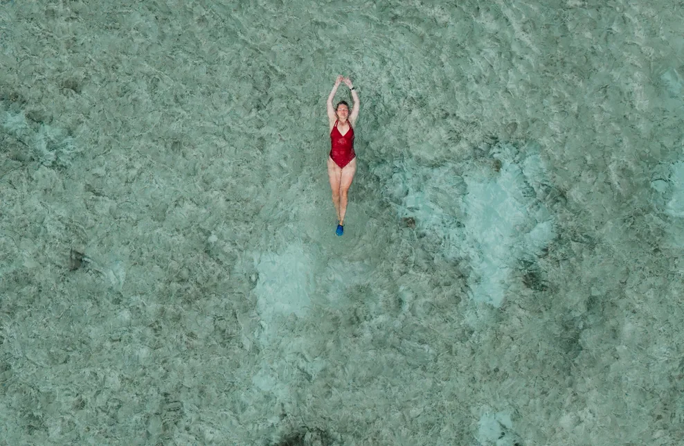 Overhead view of a swimmer floating in clear shallow turquoise water